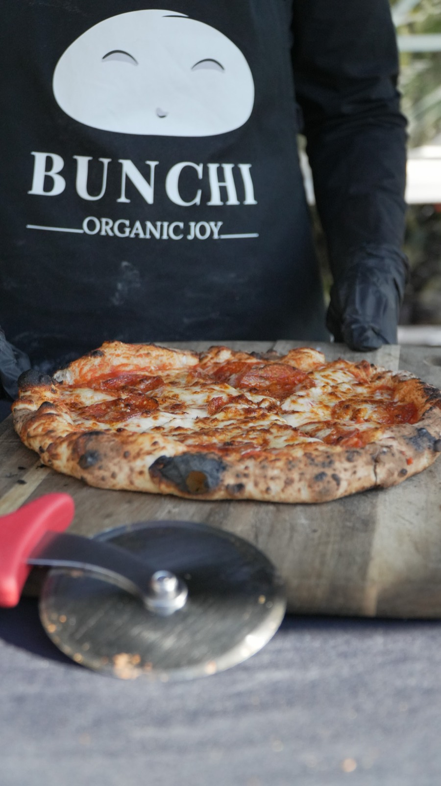 A fresh stone-baked pizza in the Bunchi apron